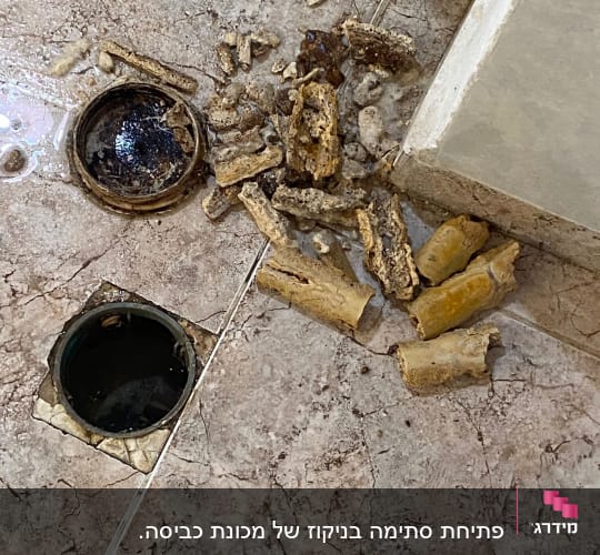 פתח ניקוז פתוח עם פסולת צינורות על הרצפה